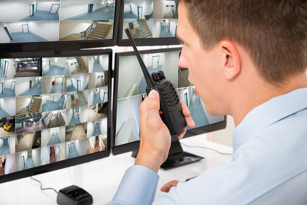 Person looking at multiple CCTV screens and using a two way radio