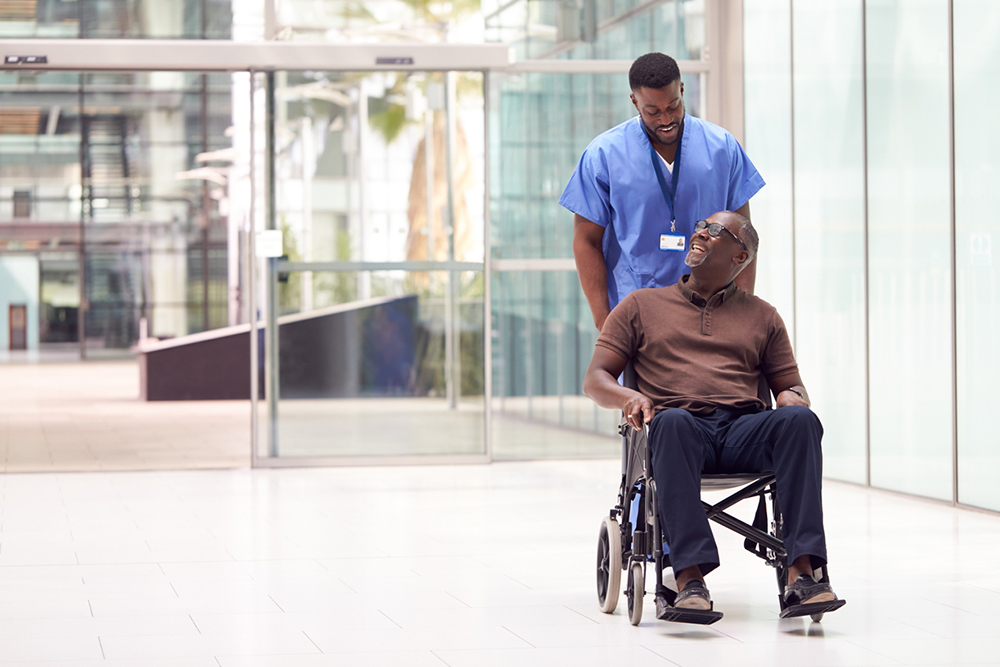 Person in medical uniform pushing a patient in a wheelchair