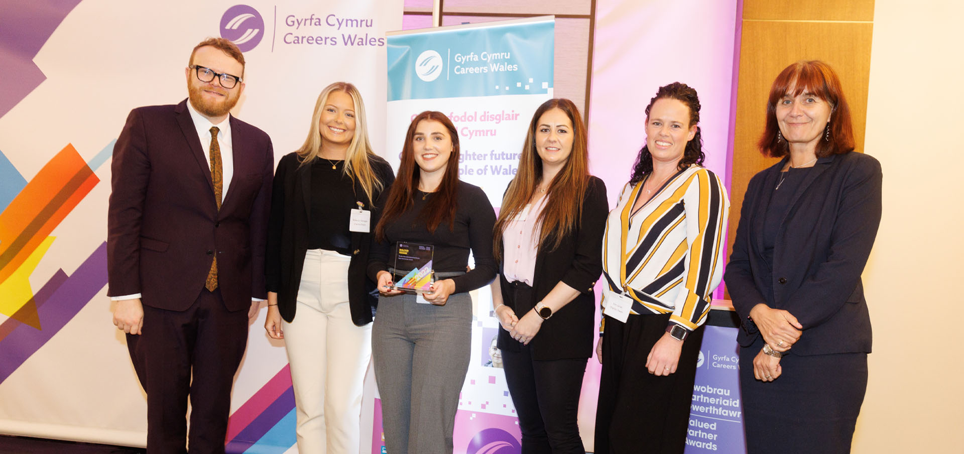 Employees from Charles Owen being presented with their award by presenter Huw Stephens and Nikki Lawrence, Chief Executive, Careers Wales
