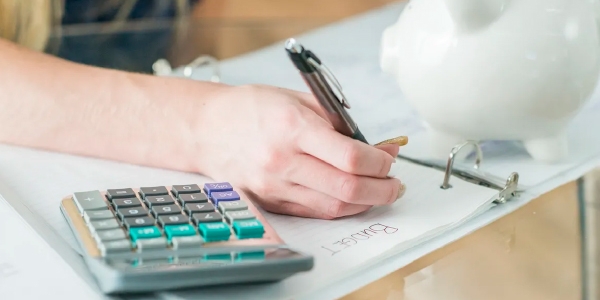 Persons hand working out finances with calculator next to them