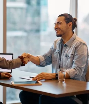 A smiling interviewee shaking hands with their interviewer